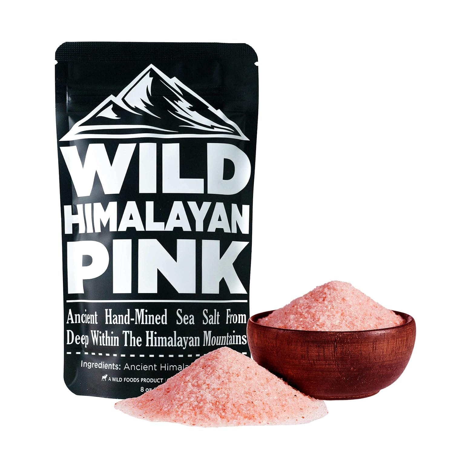 A black pouch of Wild Himalayan Pink Salt, 8 oz, featuring ancient hand-mined sea salt sourced from deep within the Himalayan Mountains. A small wooden bowl and a pile of pink salt are displayed next to the pouch.